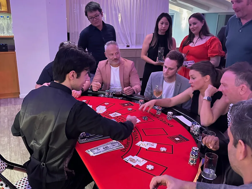 Guests playing blackjack at a red felt casino table